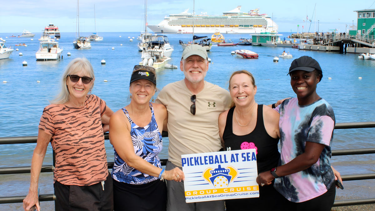 Five Pickleball At Sea Group Cruise Guests holding a group sign at the harbor, with their Royal Caribbean cruise ship behind them.