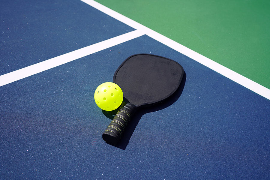 Pickleball paddle, ball and court representing the ultimate Pickleball vacation